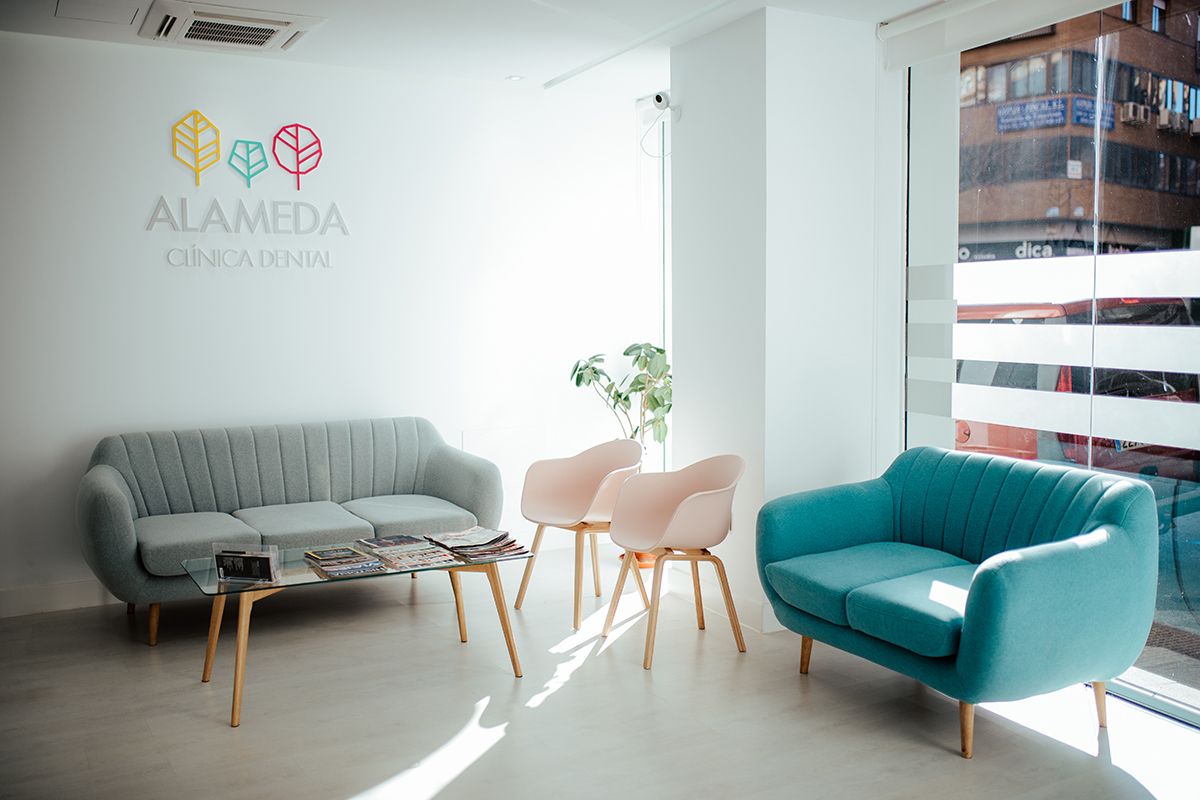 Sala de espera con sofás y el logotipo de Alameda Clínica Dental en la pared