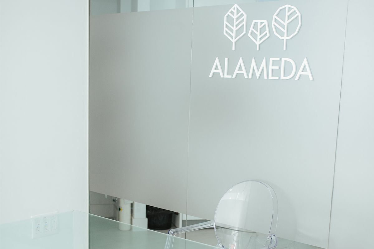 Logotipo de Alameda en blanco sobre una mampara de cristal esmerilado