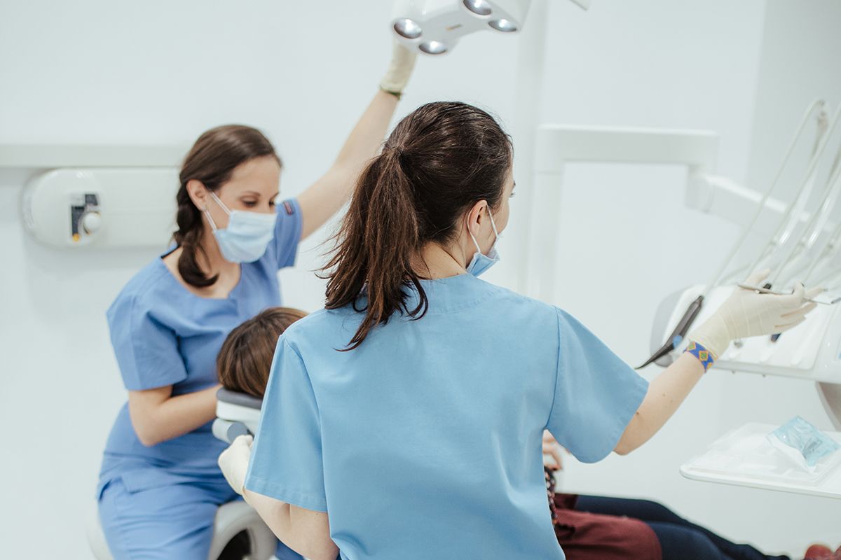 Dos profesionales de la clínica atendiendo a un paciente en el sillón dental