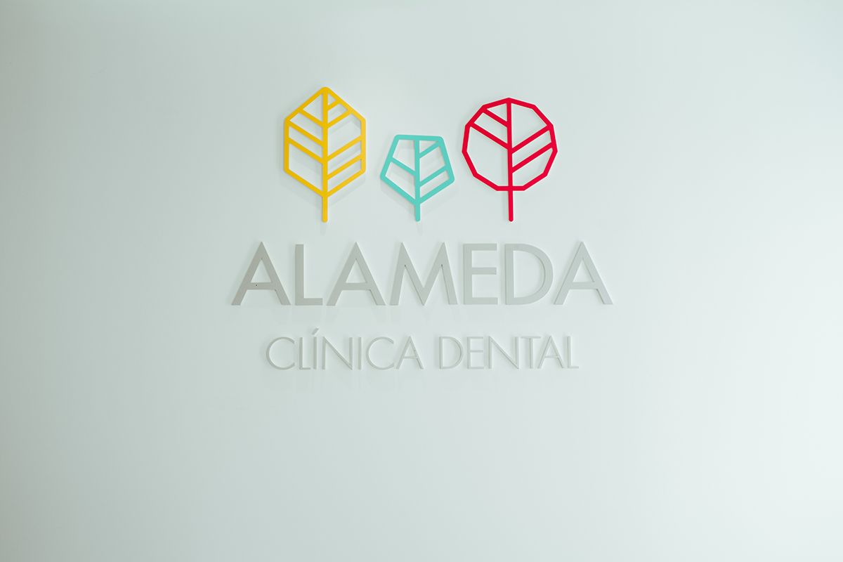 Logotipo de Alameda Clínica Dental con sus tres árboles de colores en la pared